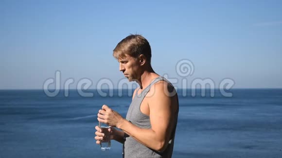 一个人从海洋上的塑料瓶里喝水运动后解渴视频的预览图