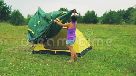 男人和女人把上篷扔到安装好的帐篷上视频的预览图