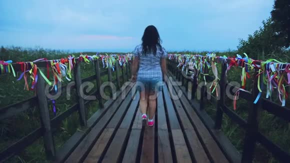 年轻女子走在木桥的角度视频的预览图