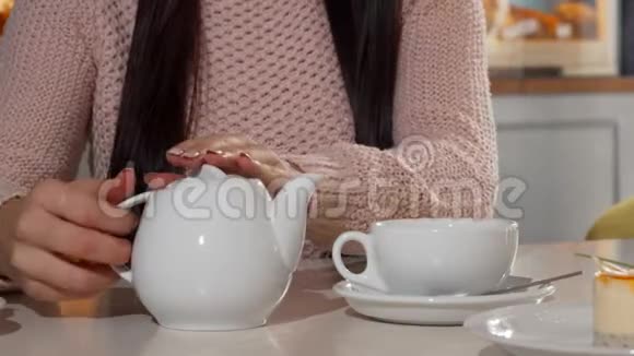 在咖啡店的女人把芳香的茶倒进杯子里视频的预览图