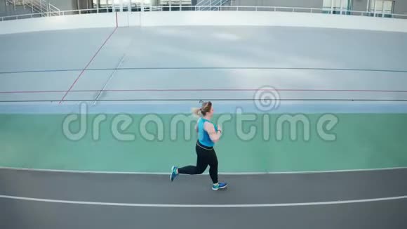 超重女性沿着跑道跑步的无人视野视频的预览图