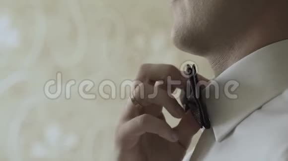 一个男人把一只蝴蝶系在脖子上视频的预览图