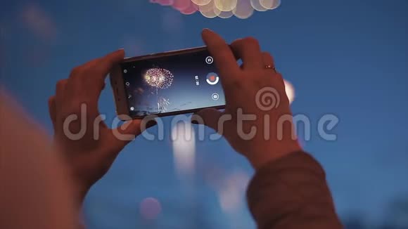 女孩在智能手机上燃放烟花女人打电话敬礼在她的智能手机上创建一个视频美丽美丽视频的预览图