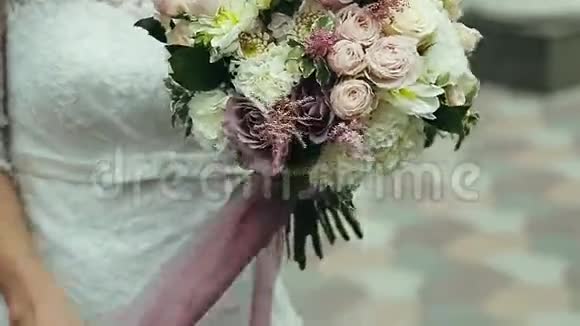 穿着婚纱的年轻女孩捧着一束新娘美丽的婚礼花束在手中视频的预览图