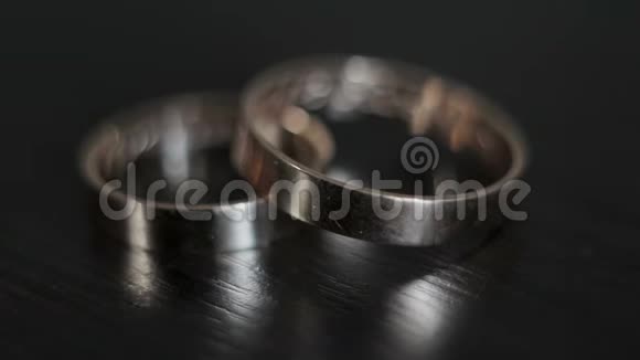 两个金色结婚戒指的特写放在一个木制的表面上在装饰品上有一道光线视频的预览图