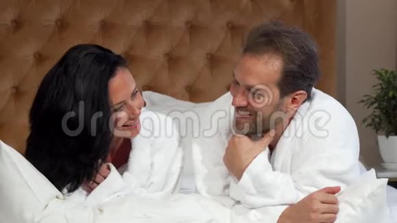 成熟的已婚夫妇穿着浴袍聊天一起躺在酒店的床上视频的预览图