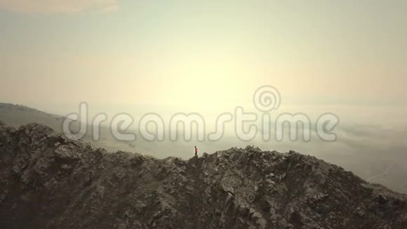空中特写秋天的一个寒冷阴天女徒步旅行者骄傲地站在山顶上视频的预览图