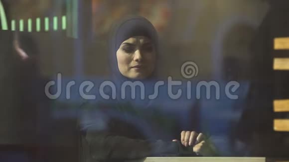 悲伤的穆斯林女士在咖啡馆里戴着传统头巾想着家移民视频的预览图