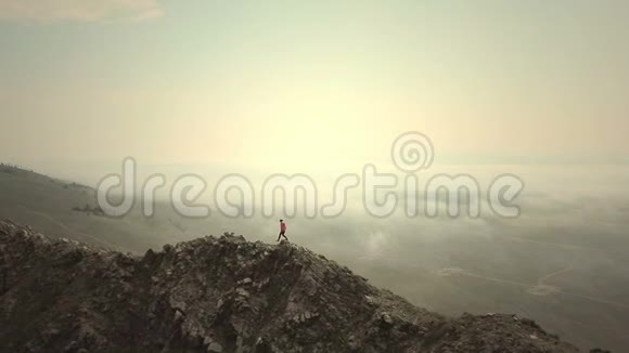 空中特写秋天的一个寒冷阴天女徒步旅行者骄傲地站在山顶上视频的预览图