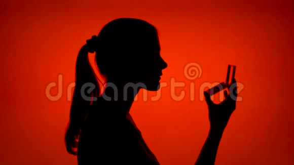 女人的剪影在睫毛上涂上睫毛膏侧写中的女性脸确实是红色背景的视频的预览图