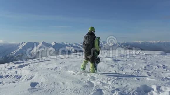 滑雪板带着滑雪板在雪山上走到山顶滑雪者在雪山峰上站起来骑马视频的预览图