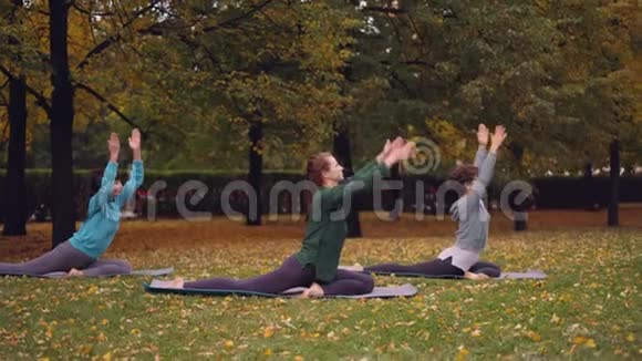 一群年轻女士正在练习瑜伽在美丽的绿色和美丽的垫子上练习鸽子国王的姿势EkaPadaRajakapotasana视频的预览图