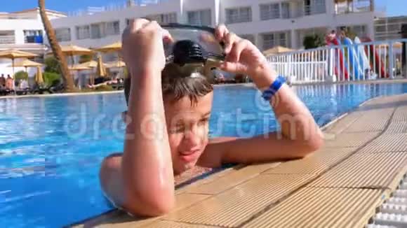 在埃及酒店的蓝水池里放松潜水面具的快乐男孩视频的预览图