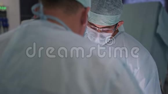 两名医生在手术期间穿着无菌衣服和口罩手术室的外科医生视频的预览图