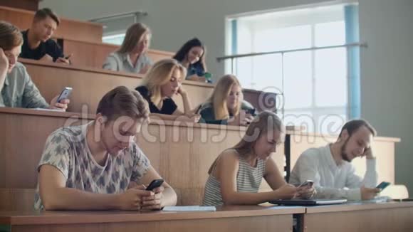 多民族学生在讲座期间使用智能手机青年在学习期间使用社交媒体视频的预览图