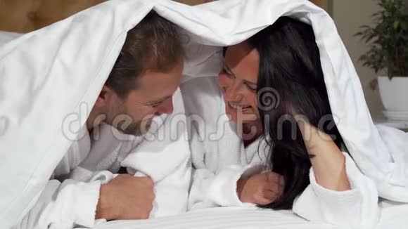 快乐的成熟夫妻快乐地笑着躺在床上视频的预览图
