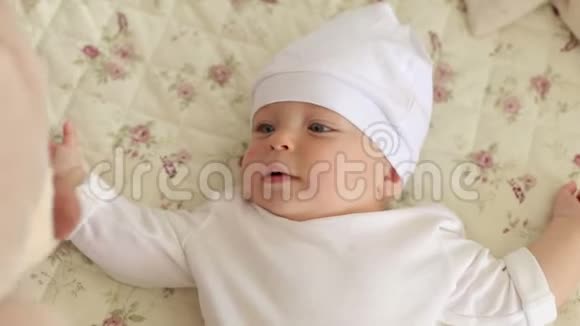 一个戴着白色帽子的新生男孩躺在家里的床上戴着泰迪熊视频的预览图