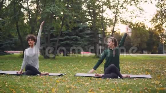 勤奋的瑜伽学生正在学习牛脸的位置坐在垫子上伸展手臂而有经验的老师视频的预览图