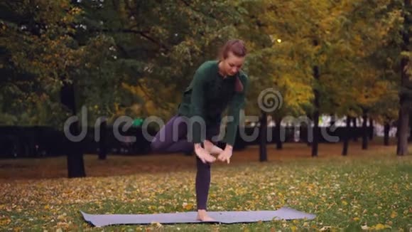灵活的年轻女子正在平衡一只脚牵着手在纳马斯特享受个人实践在公园美丽美丽视频的预览图