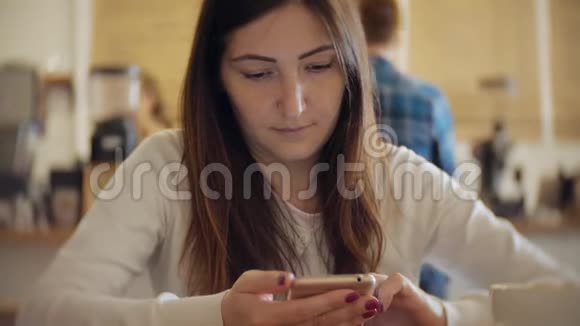 带着咖啡的微笑小姐在咖啡馆里用手机聊天视频的预览图