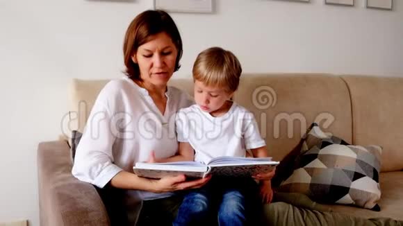 一个女人在客厅的沙发上给儿子读一本书视频的预览图