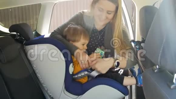 年轻母亲将她的小儿子安置在儿童安全座椅和调整皮带的4k视频使用特殊座位的有爱心家长视频的预览图