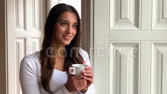 美丽的少女喝着咖啡在咖啡馆里微笑视频的预览图