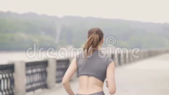 运动女运动员在城市堤岸跑步户外训练后景视频的预览图