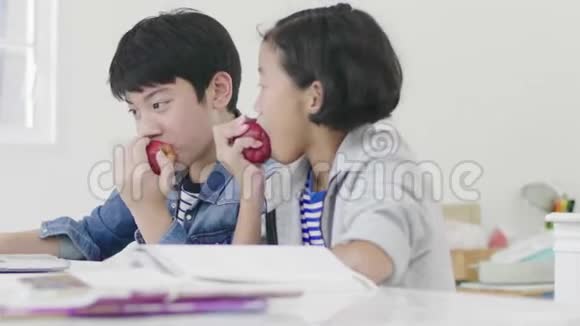 两个孩子都在吃苹果同时做家庭作业视频的预览图