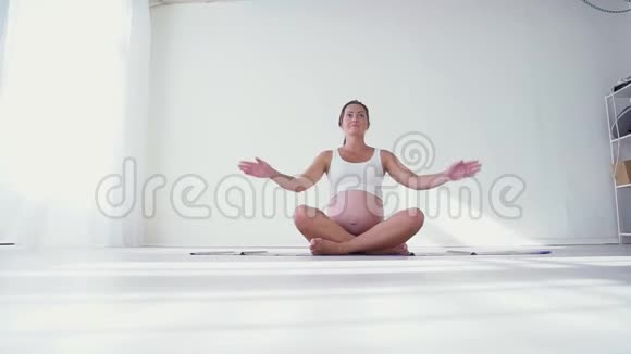怀孕的年轻女性在瑜伽垫上做运动视频的预览图