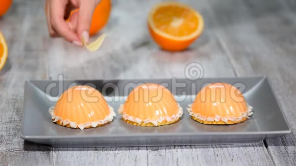 创造美味甜点的过程无法辨认的糖果手装饰橙色釉面蛋糕视频的预览图