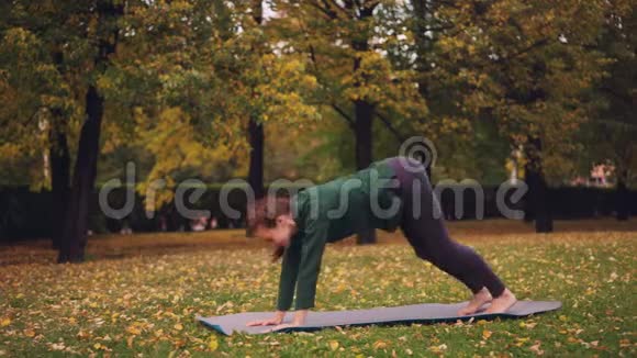 在城市公园站在垫子上的个人练习中一位开朗的年轻女性正在做瑜伽平衡练习视频的预览图