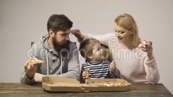 营养概念美味的披萨妈妈爸爸和儿子在白色背景下一起吃披萨幸福家庭概念视频的预览图