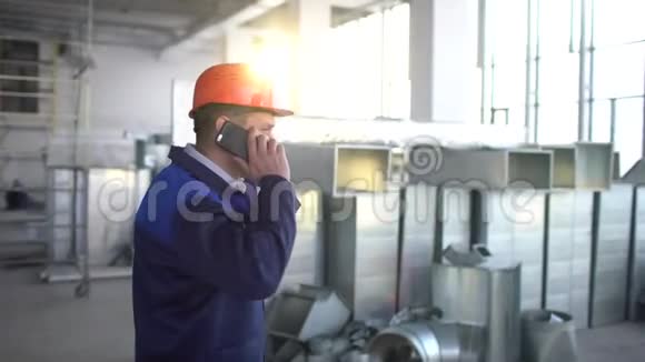 年轻的白种人工程师在正在建造的大楼里打电话戴橙色安全帽的档案馆视频的预览图