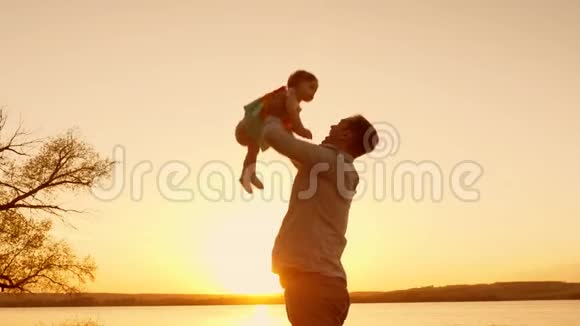 爸爸辗转婴儿亲吻她的脸颊在日落时微笑慢动作视频的预览图