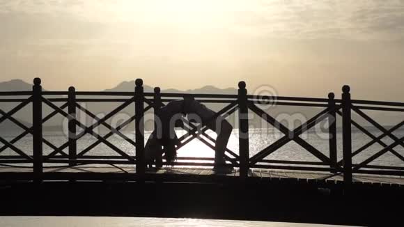 日出时在桥上慢动作做瑜伽的女孩视频的预览图