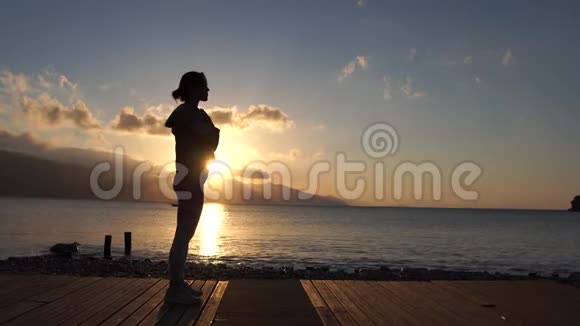日落时分年轻女孩在海边慢动作练习能量视频的预览图