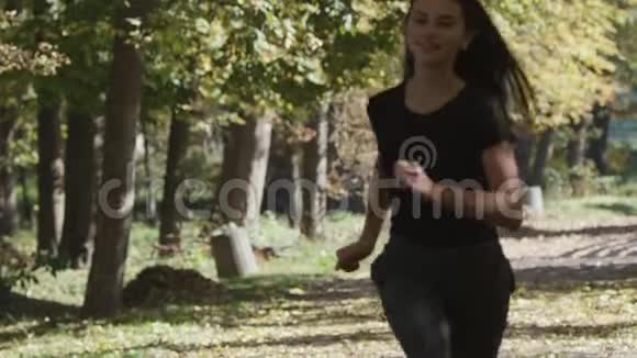 一个女孩跑在森林公园的一个弯道上镜头从前方120fps追踪她视频的预览图