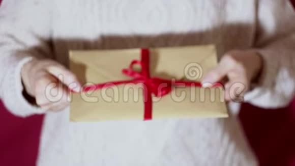 漂亮的女孩拿着一个带有红色丝带的礼物信封漂亮的女孩手里拿着一个带有红丝带的礼物信封视频的预览图