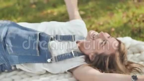这个女孩很高兴因为她满足了她的欲望夏天躺在公园里的一个美利奴格子呢上吹吹风视频的预览图