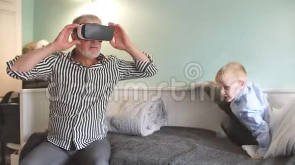 男孩和他爷爷在家里的沙发上用VR眼镜视频的预览图