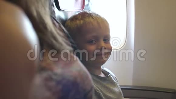 靠窗坐在飞机座位上的小男孩的肖像视频的预览图