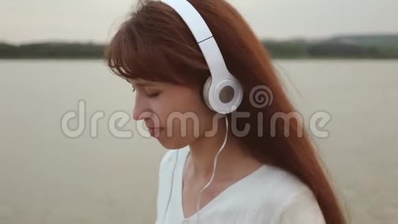 戴着耳机的快乐女孩去海滩听音乐视频的预览图