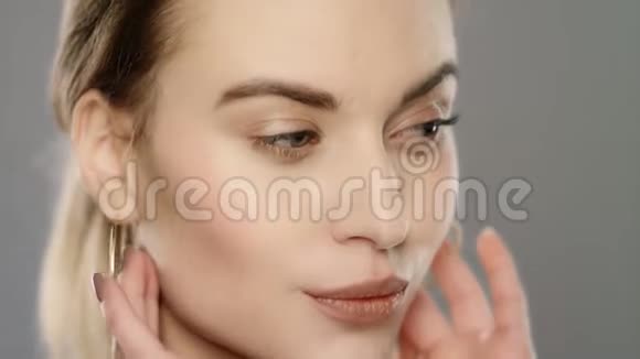 美容模特在缓慢运动中触摸面部皮肤靠近年轻女子的脸视频的预览图