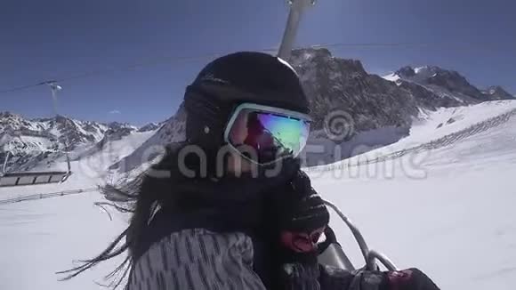 滑雪场升降椅上美丽的滑雪板女孩视频的预览图