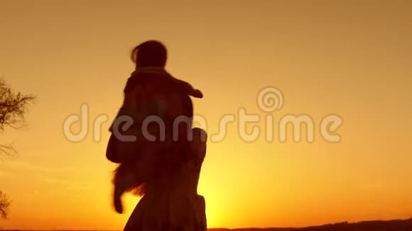 妈妈在日落时和小孩子跳舞快乐的一家人夏天在公园散步视频的预览图