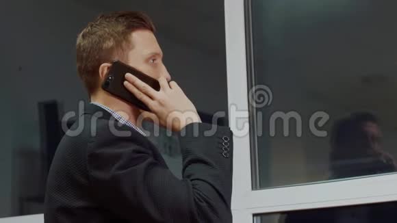 从后面看近景的人透过窗户看同时通过手机打晚上办公室视频的预览图