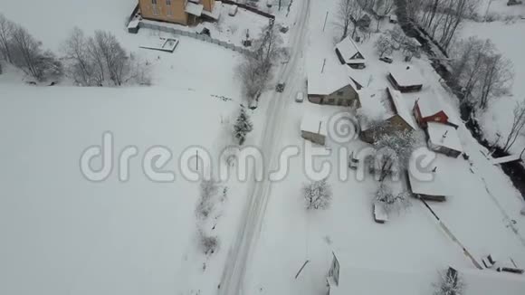 在喀尔巴阡村的冬季公路上行驶的一辆汽车上快速飞行鸟雪覆盖的房子的视野农村视频的预览图