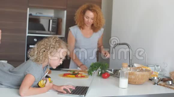 女人在网上做饭女儿在厨房里看菜谱视频的预览图