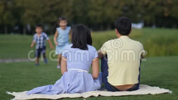 可爱的亚洲孩子温柔地拥抱公园里的父母视频的预览图